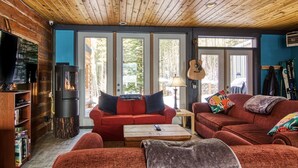 A cozy living room with a fireplace, red sofas, and a television. - Earl Grey Lodge (Panorama)
