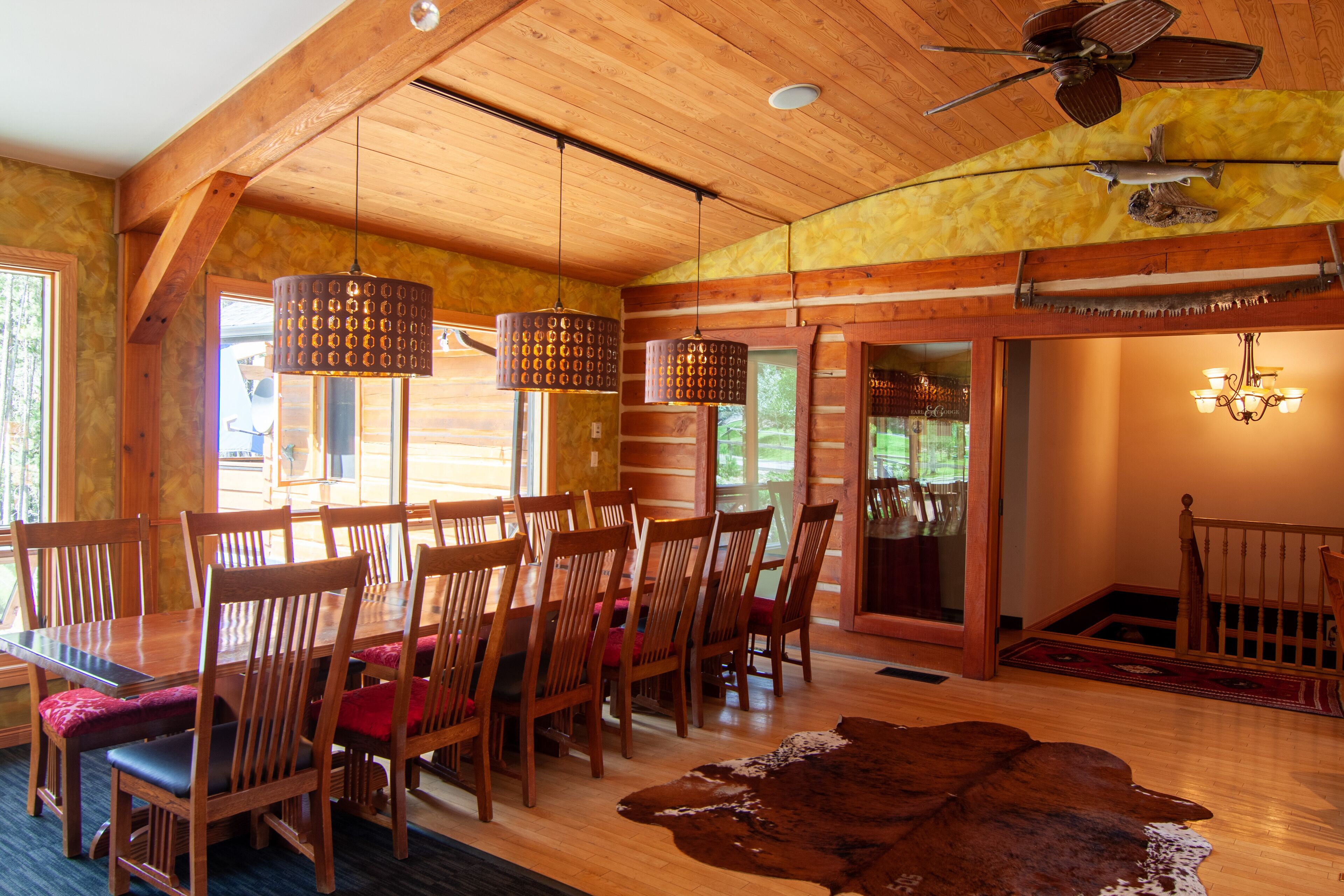 Un coin repas en bois, avec une table et des chaises, un ventilateur de plafond et un luminaire suspendu.