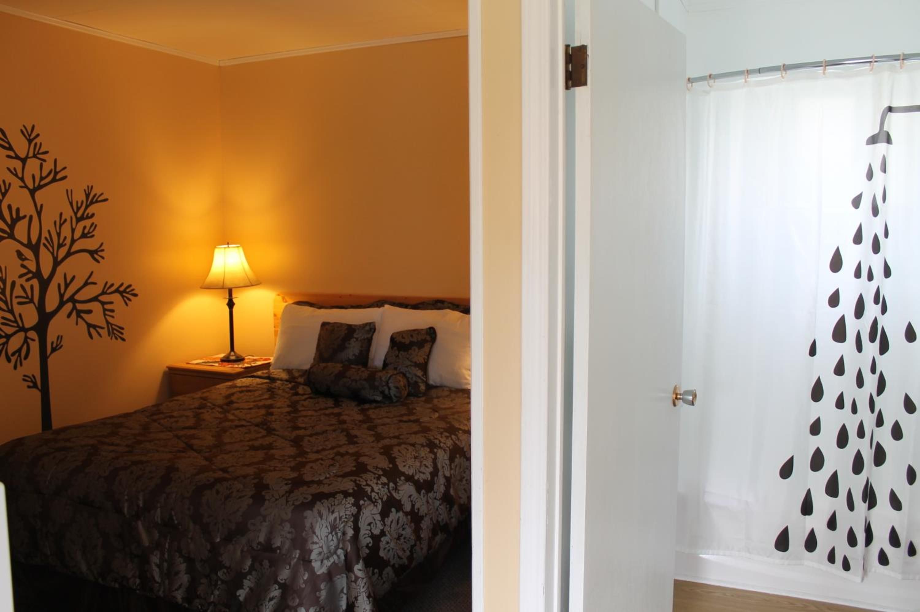 A bedroom with a bed, a nightstand, a lamp, and a wall decoration.