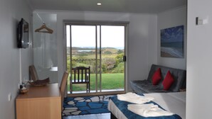 A bedroom with a bed, a dresser, a chair, and a view through a sliding door.