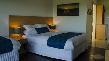 A hotel room with a large bed, two bedside tables with lamps, a painting on the wall, and a wooden cabinet.