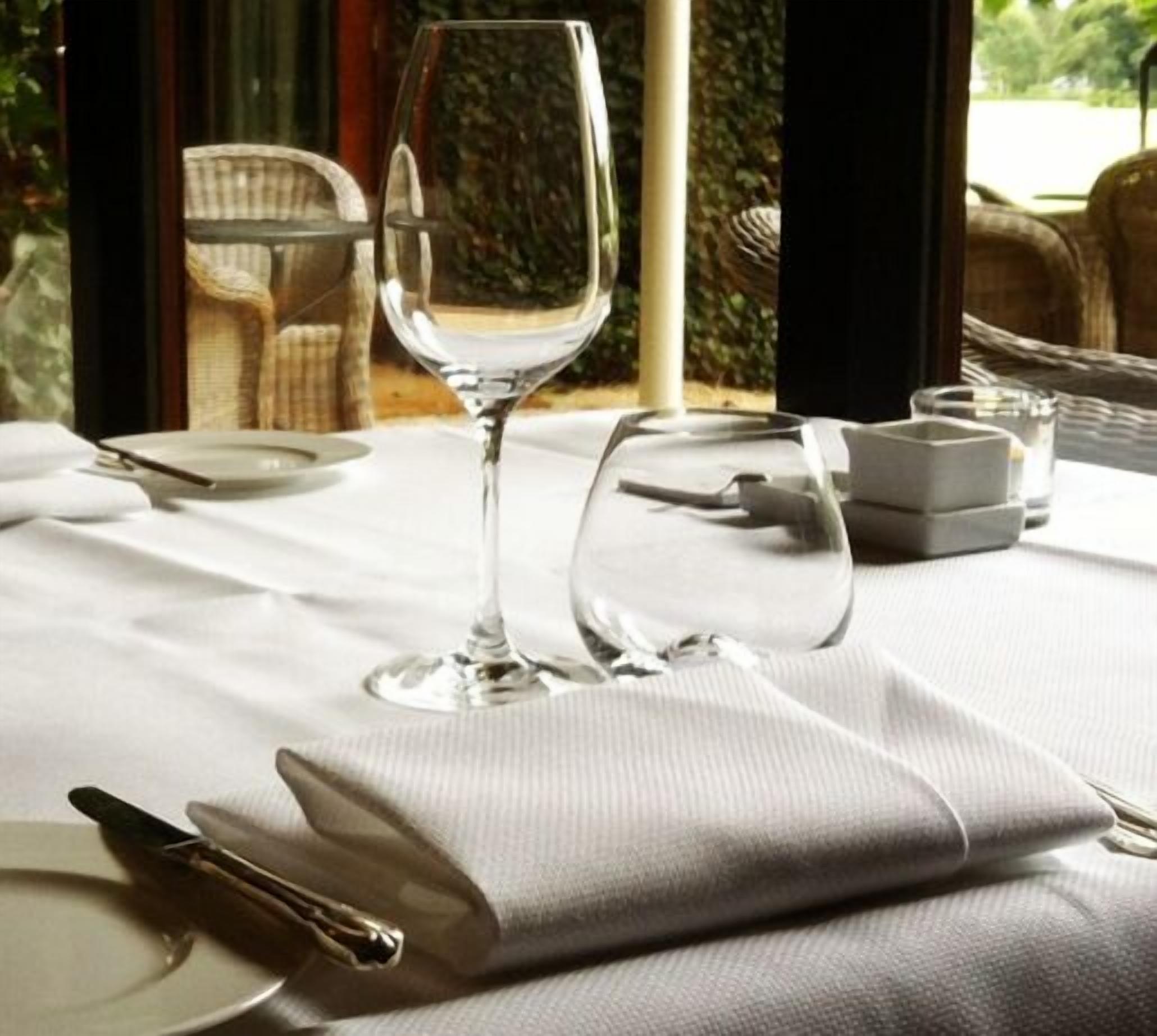 A table set for dining with a wine glass and a water glass, a folded napkin, and a plate.