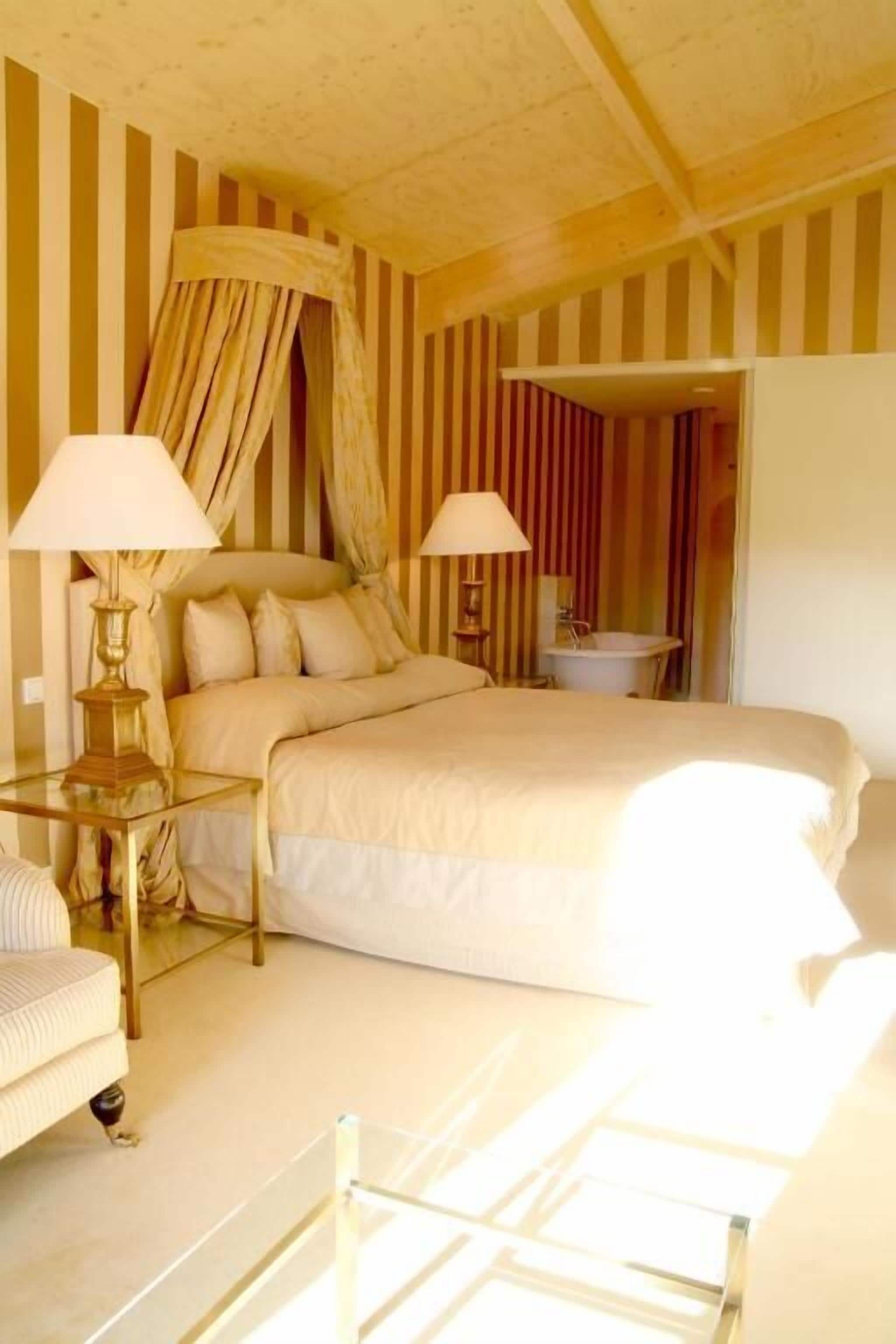 Habitación de hotel con una cama grande, dos lámparas de noche, una mesita y una silla.