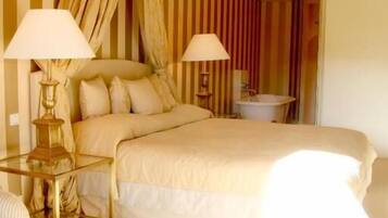 Habitación de hotel con una cama grande, dos lámparas de noche, una mesita y una silla.