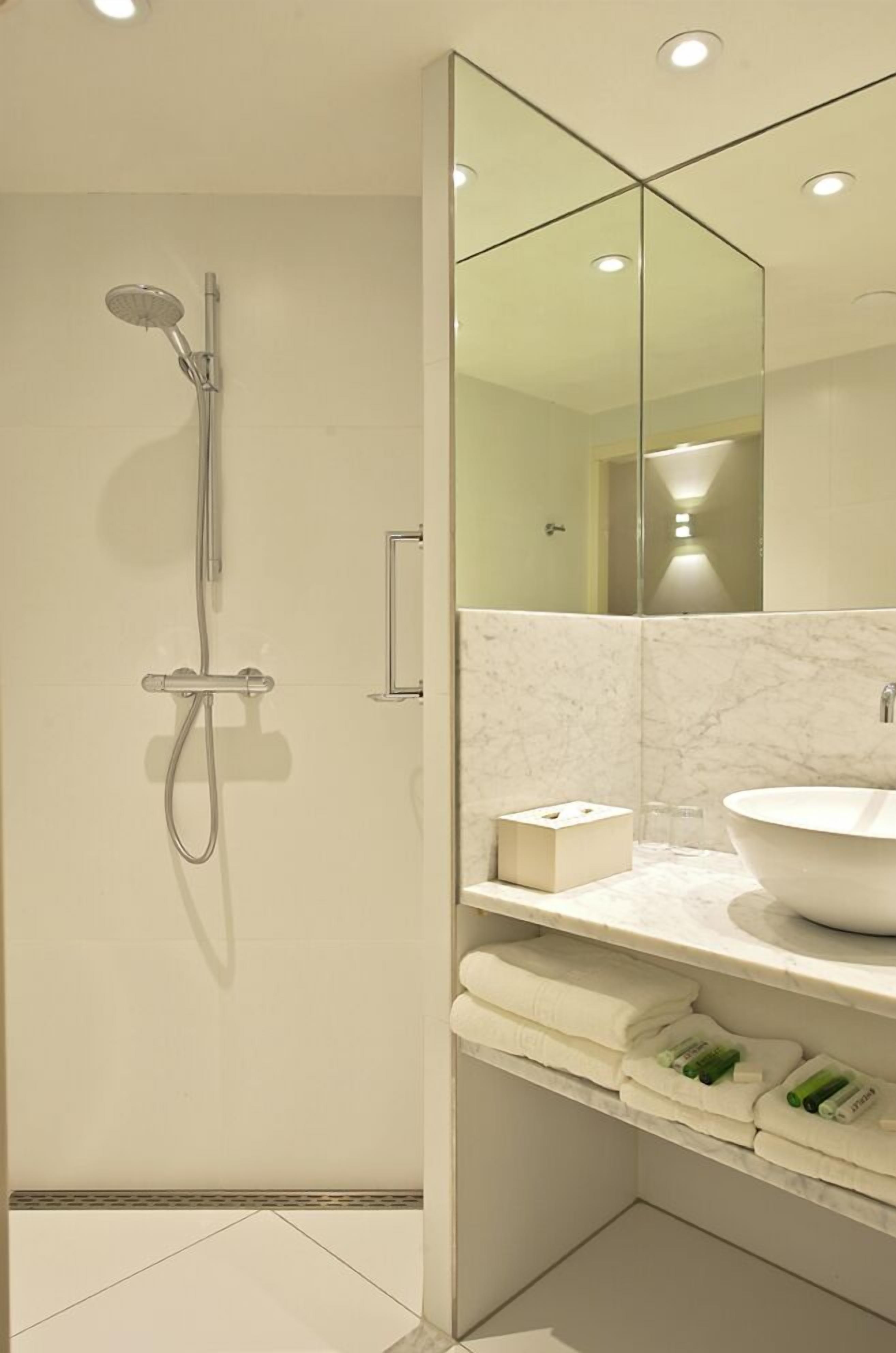 A modern bathroom with a glass-enclosed shower, a white sink, and a marble countertop.