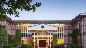 A modern building with a symmetrical facade, large windows, and a central entrance with a sun-like design. - Restaurant Hotel Merlet  (Schoorl)