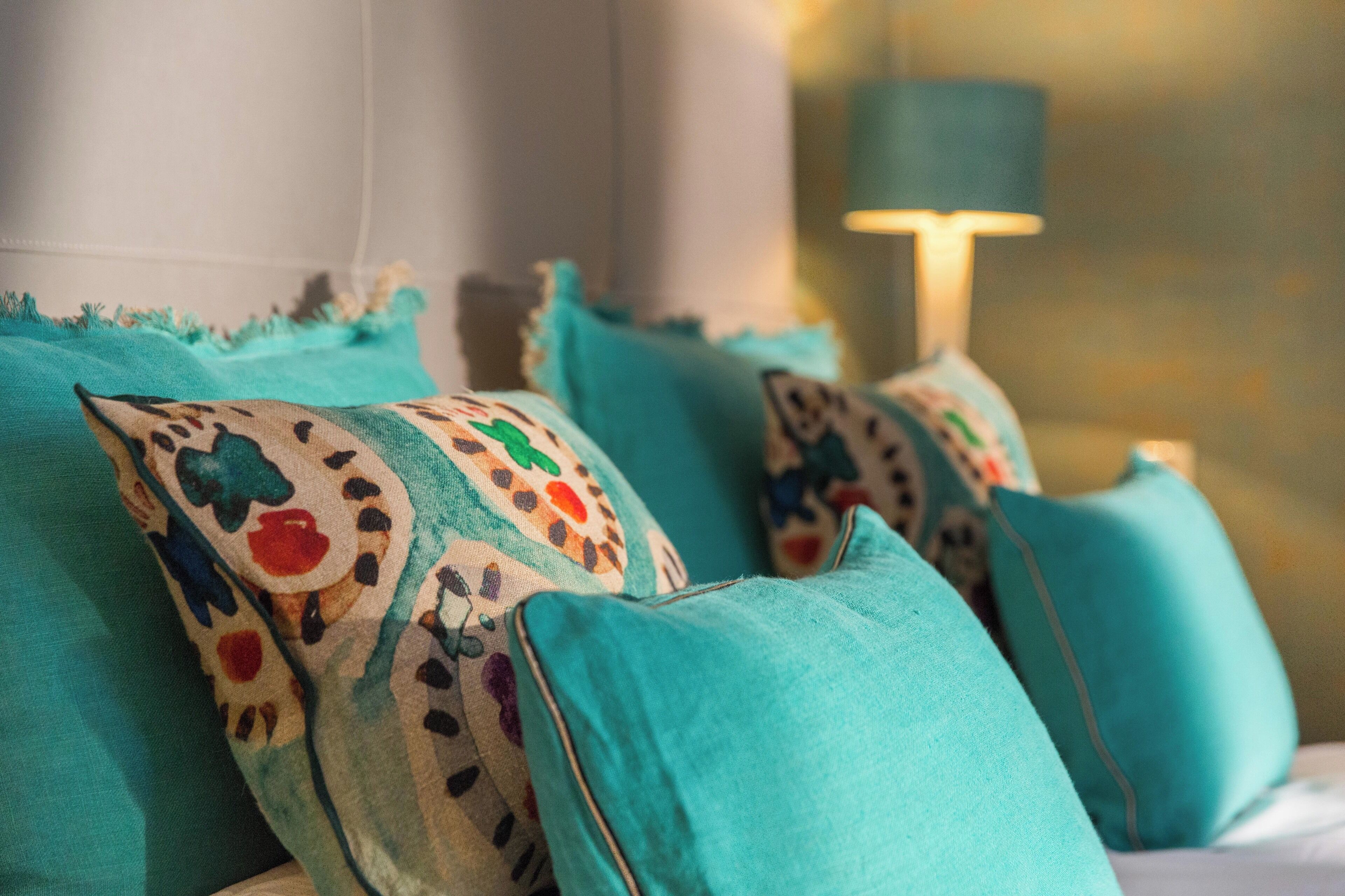 A bed with teal pillows and a patterned pillow.