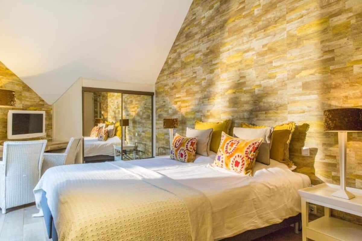 A modern bedroom with a large bed, a television, and a seating area.