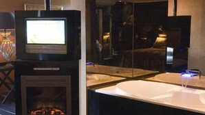A modern bathroom with a fireplace, a large mirror, and a sink. - Restaurant Hotel Merlet  (Schoorl)