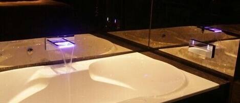 A modern bathroom with a large, white sink and a mirror above it.