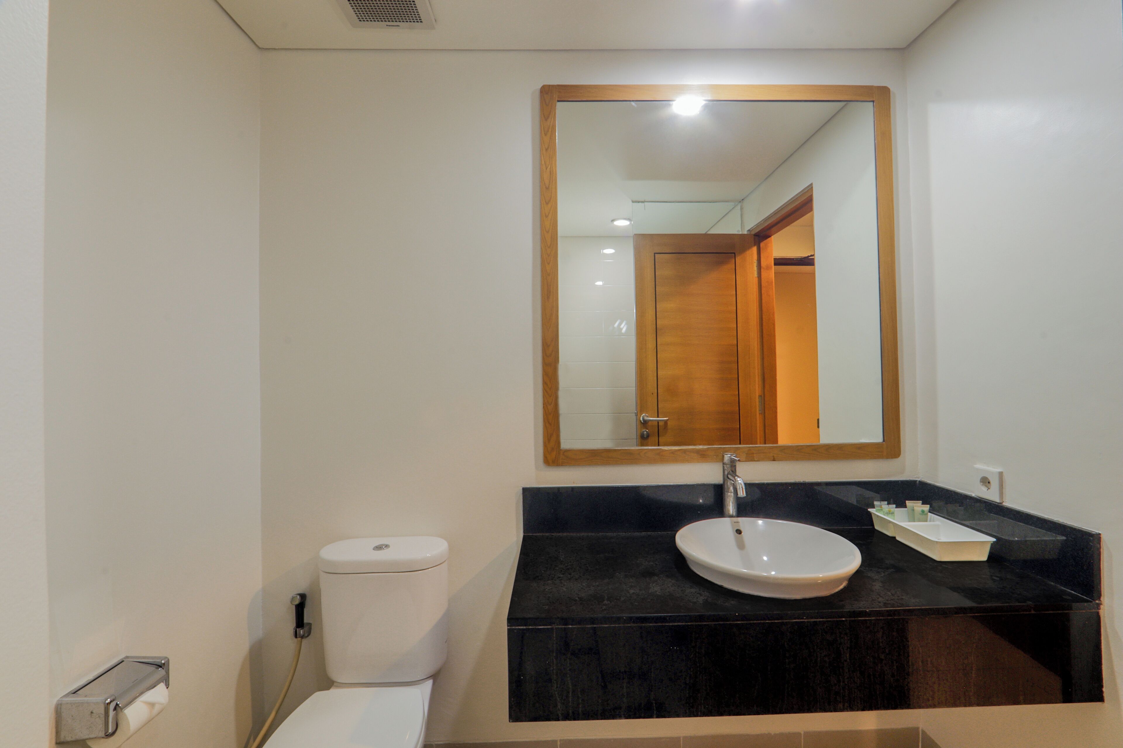 A bathroom with a toilet, sink, and mirror.