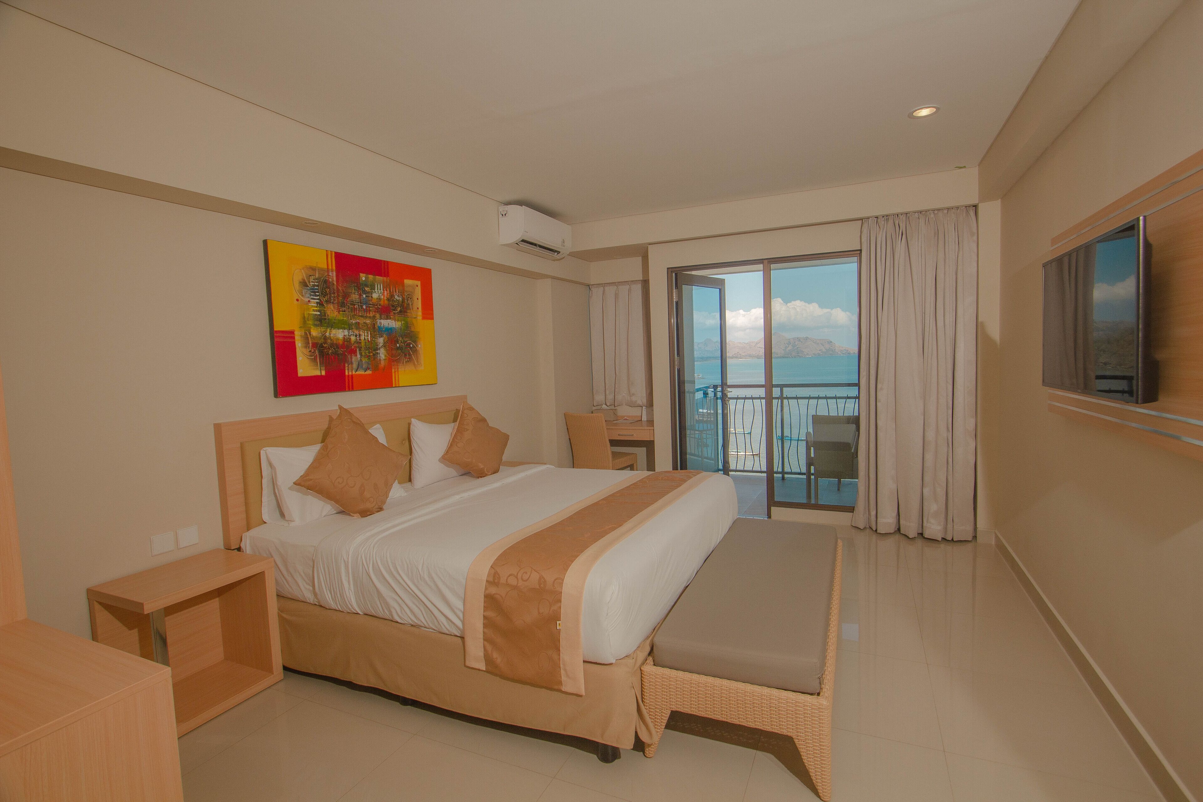 Une chambre d’hôtel moderne dotée d’un grand lit, d’un balcon avec vue et d’une télévision à écran plat.