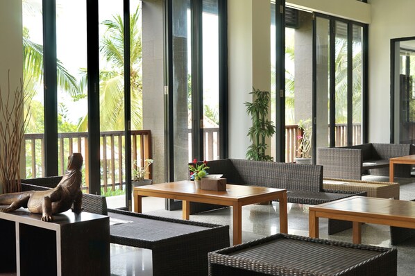 A modern lounge area with wicker furniture, large windows, and a statue.