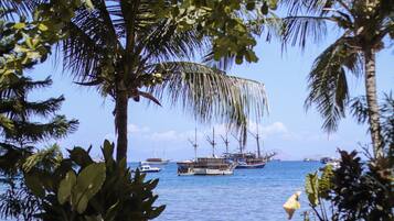 A coastal scene with several boats anchored in the water, surrounded by palm trees and clear skies.