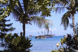 A coastal scene with several boats anchored in the water, surrounded by palm trees and clear skies. - LAPRIMA Hotel Flores (Labuan Bajo)