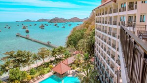 A hotel with a pool, a pier, and boats on the water. - LAPRIMA Hotel Flores (Labuan Bajo)