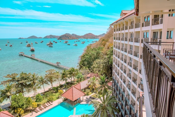 A hotel with a pool, a pier, and boats on the water. - LAPRIMA Hotel Flores (Labuan Bajo)