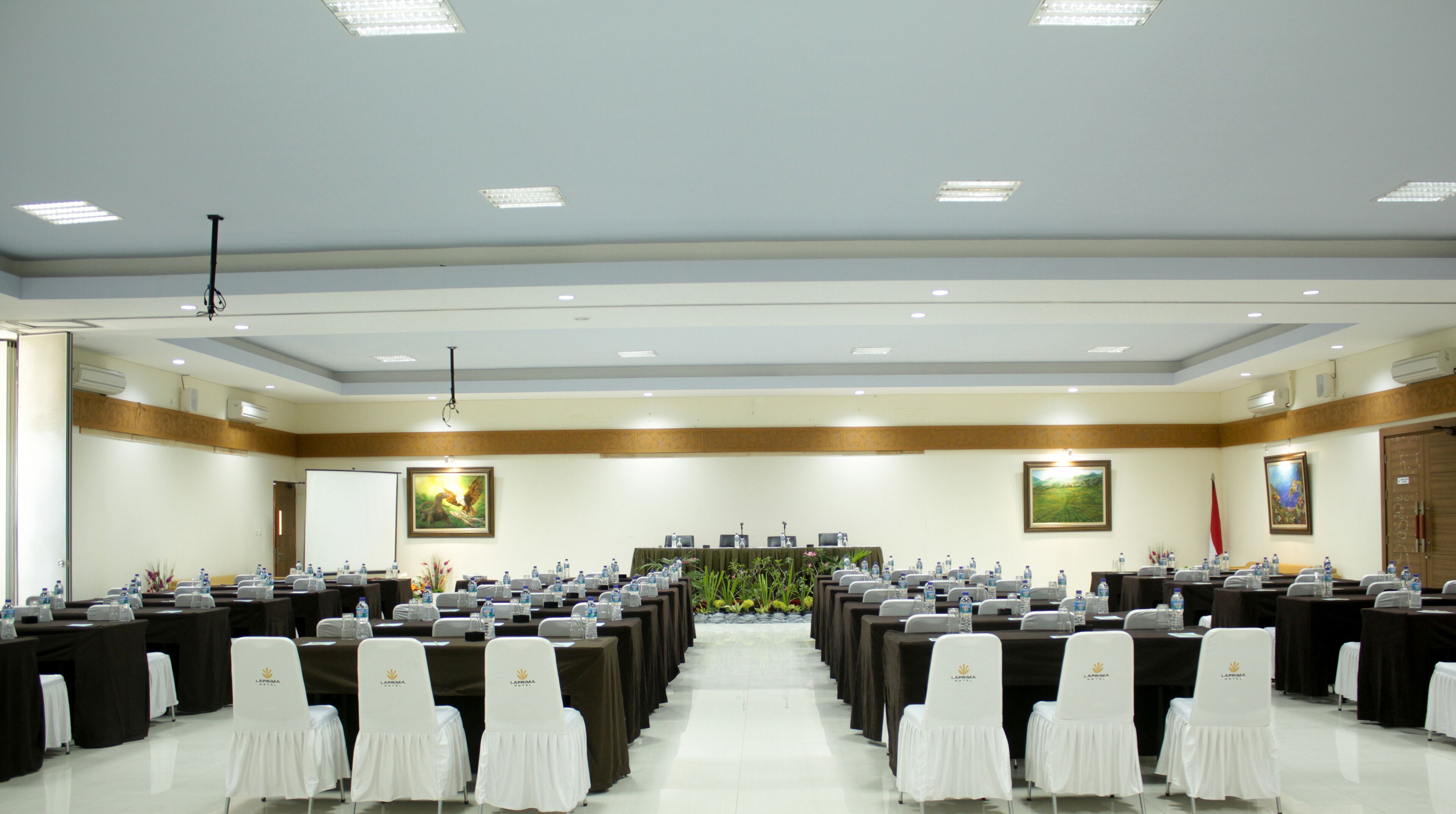 A conference room with rows of tables and chairs, equipped with nameplates and water bottles.