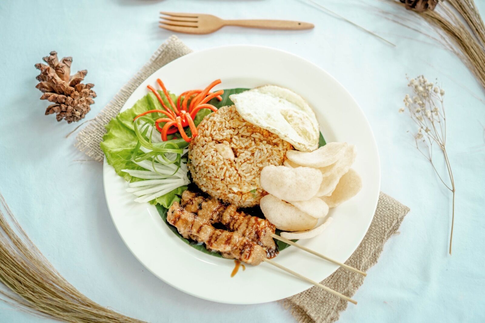 A plate of food with rice, meat, vegetables, and a fried egg on a white plate.