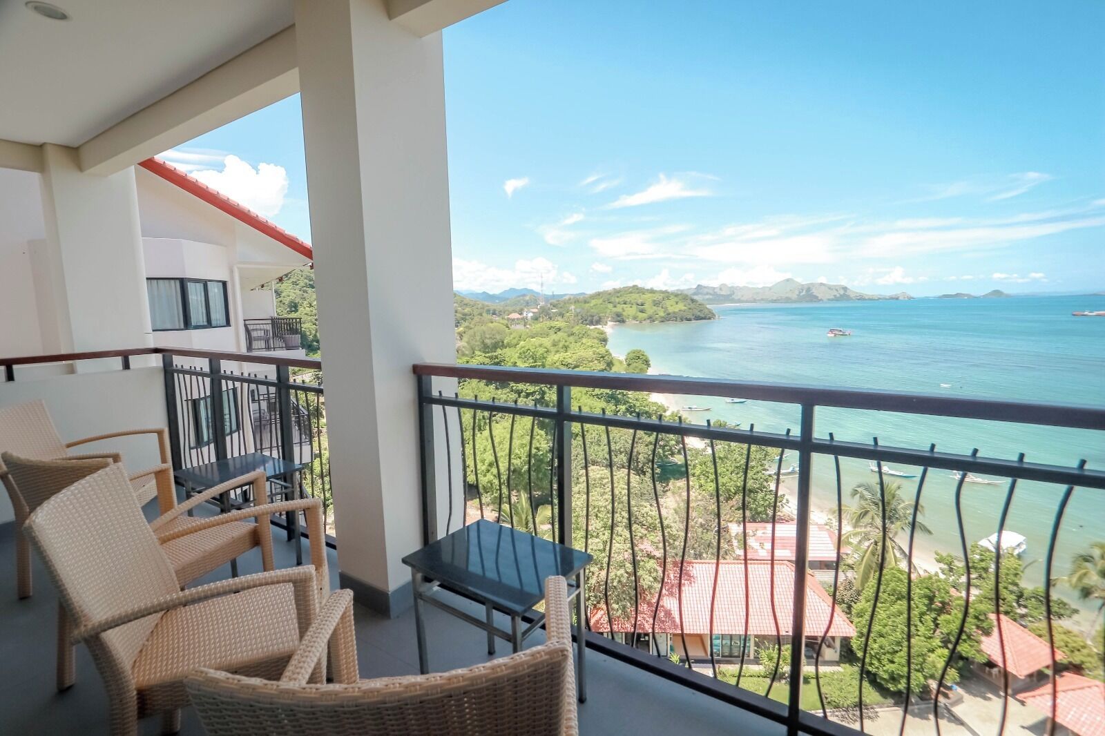 A balcony with wicker furniture and a view of a coastal landscape.