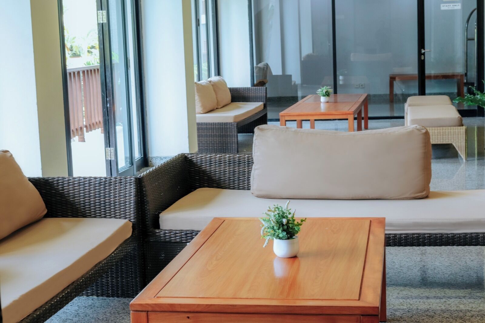 A modern lounge area with wicker furniture, a wooden coffee table, and a potted plant.
