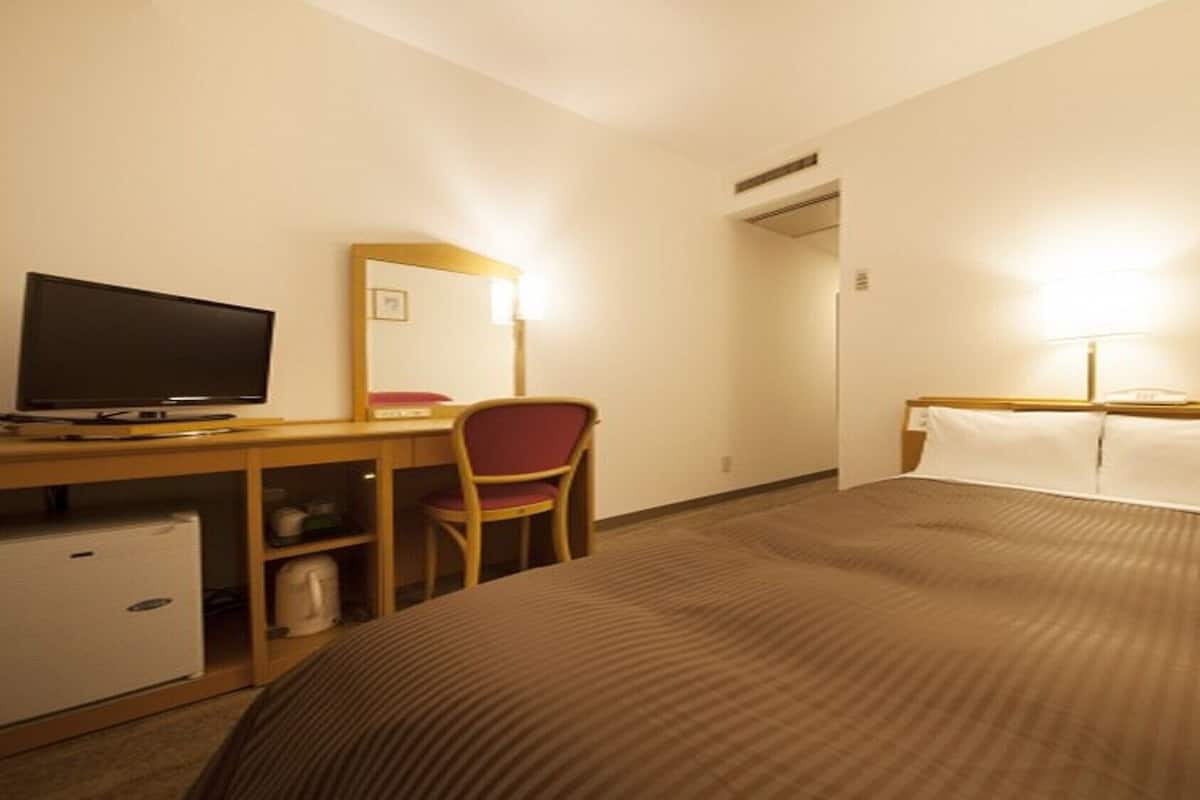 Une chambre d’hôtel comprenant un lit, un bureau avec un ordinateur, une chaise et un téléviseur.