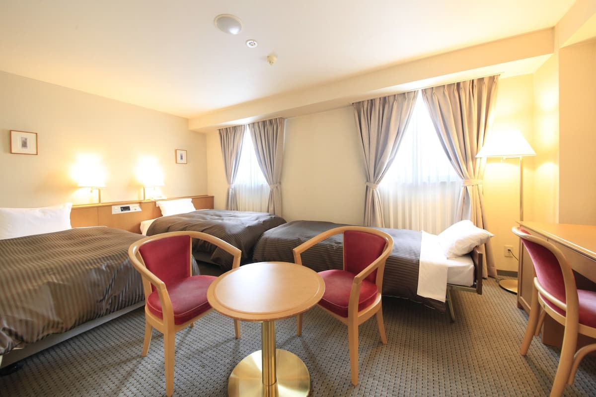 Une chambre d’hôtel avec deux lits, une table ronde et deux chaises.