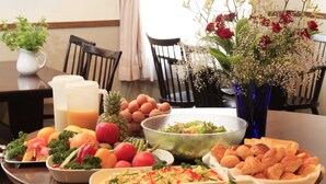 A breakfast buffet with various dishes, fruits, and a vase of flowers. - Hotel Morschein (Matsumoto)