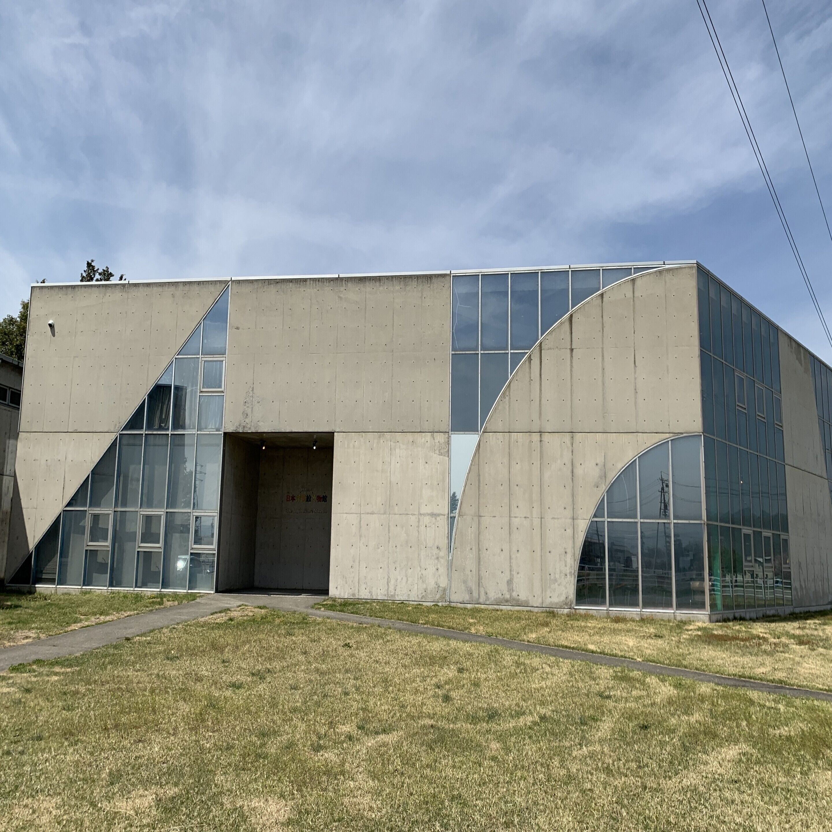 A modern building with a concrete facade, large glass windows, and a central entrance.