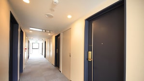 A hotel corridor with doors, a carpeted floor, and recessed lighting. - Hotel Morschein (Matsumoto)