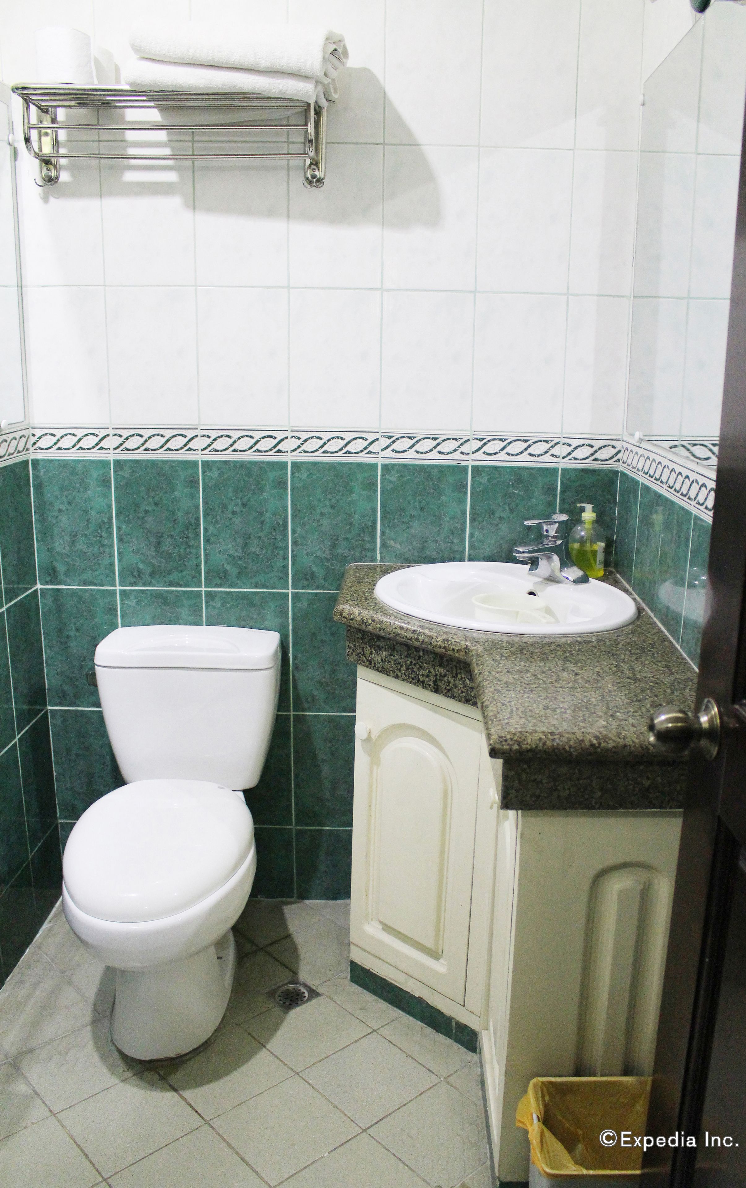 Uma casa de banho com sanita, lavatório e suporte para toalhas.