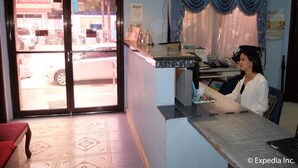Zona de recepción de hotel con un cartel de 'Gracias', un cartel de 'EMPUJAR' y relojes en la pared.