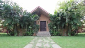 A building with a brown facade, a black door, and a stone pathway leading to the entrance. - Dream Valley Resort (Hyderabad)