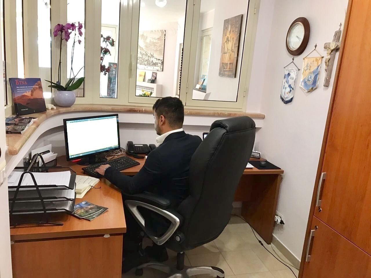 A man working at a desk with a computer, papers, and a phone.