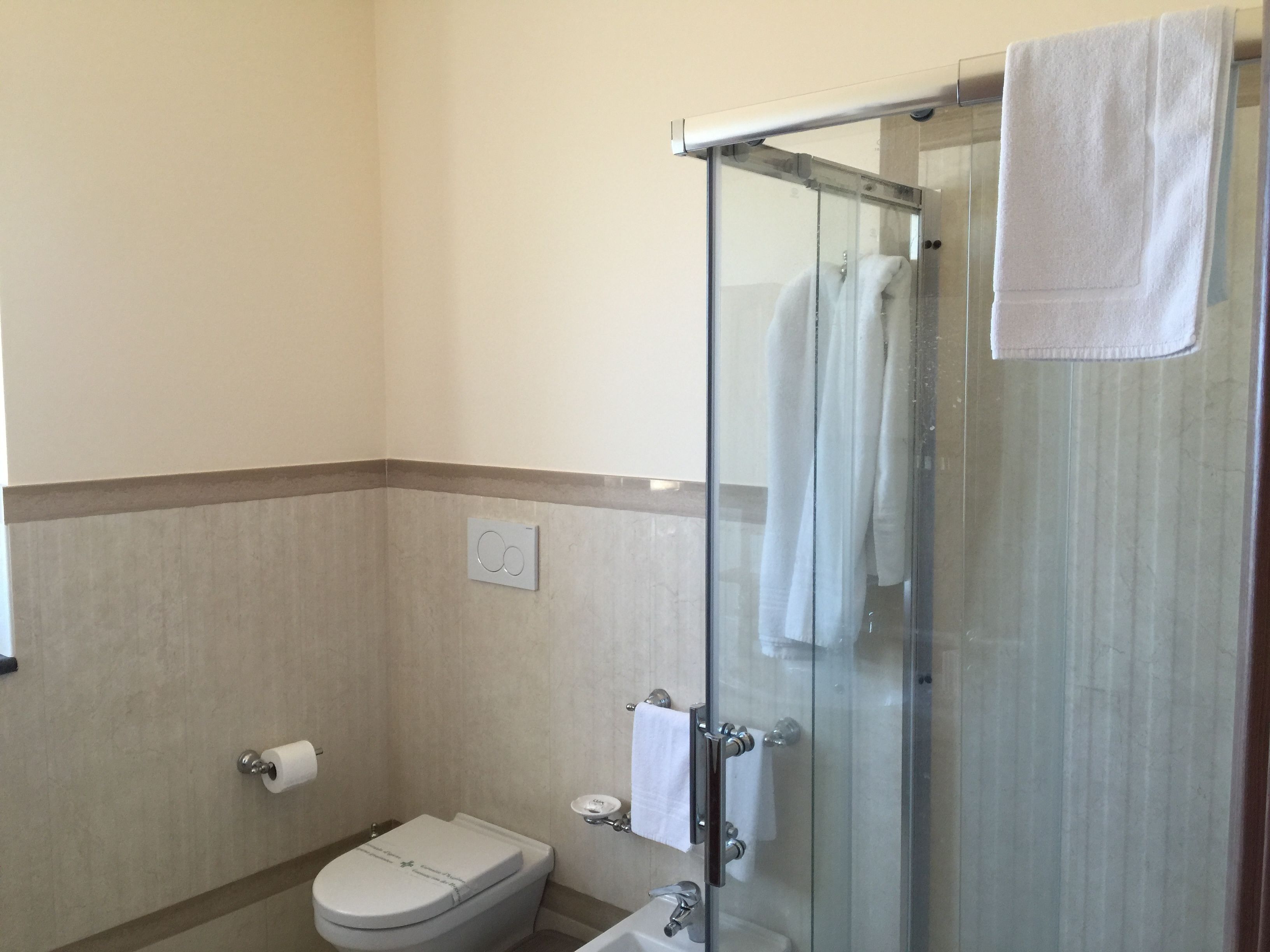 Un baño con cabina de ducha de vidrio, inodoro y lavamanos.