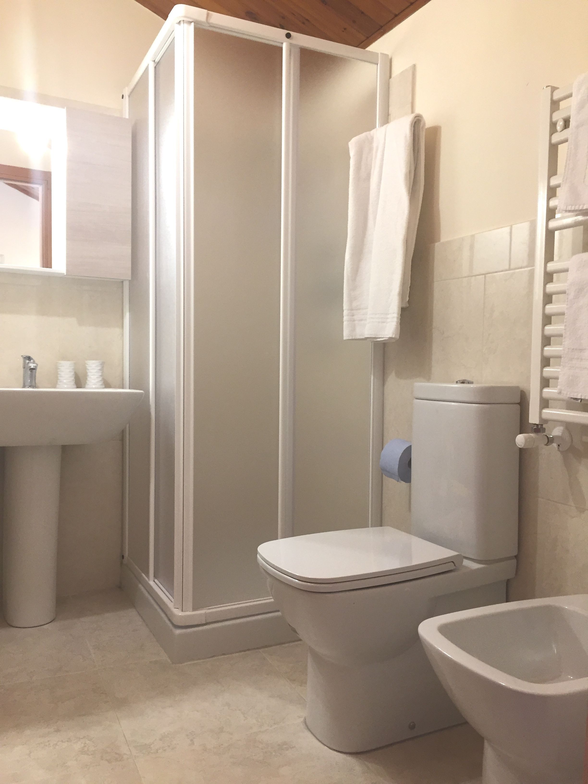 Een badkamer met douchecabine, toilet, bidet en wastafel.