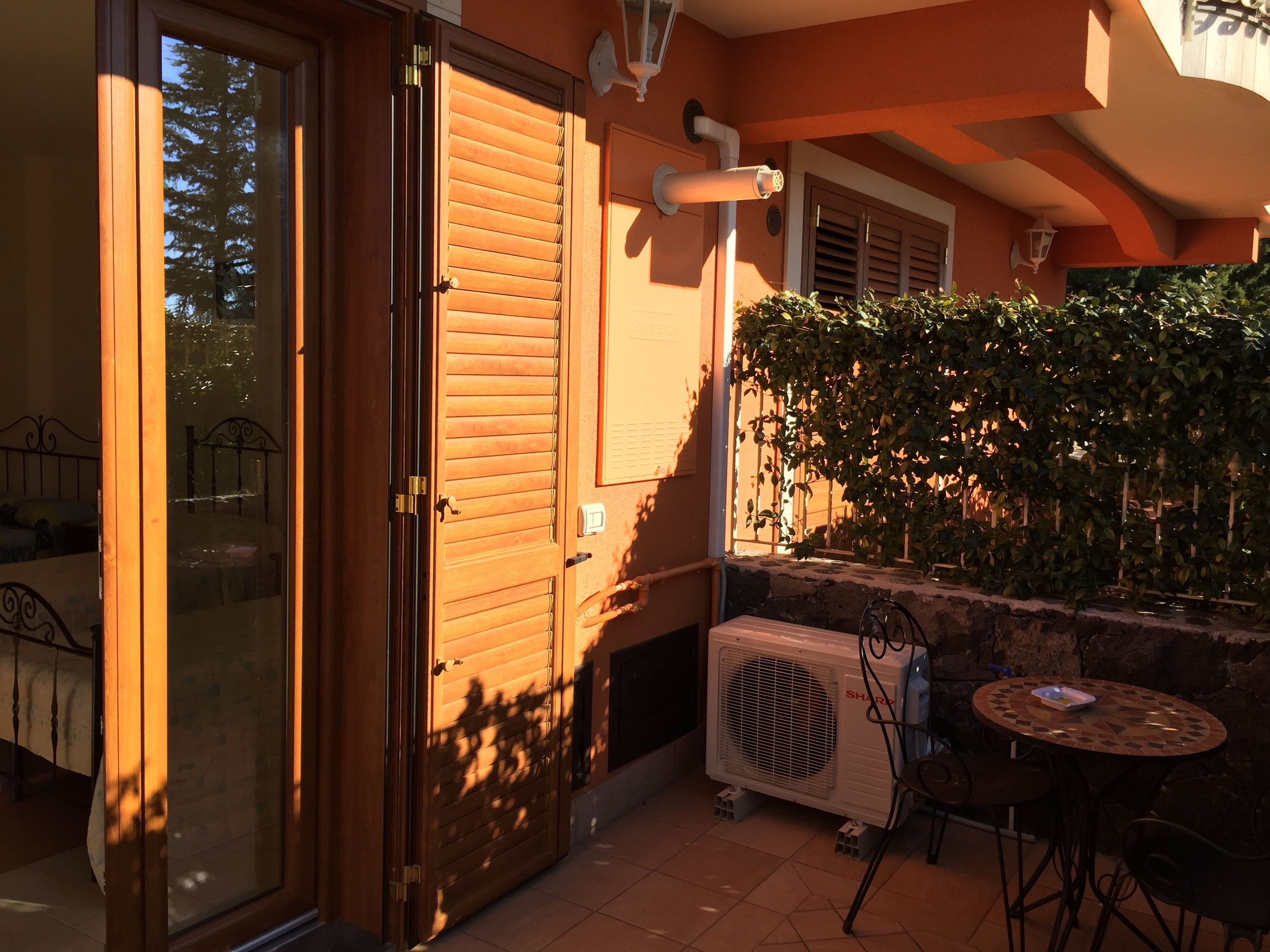 A patio area with a sliding glass door, a small table with chairs, and an air conditioning unit.