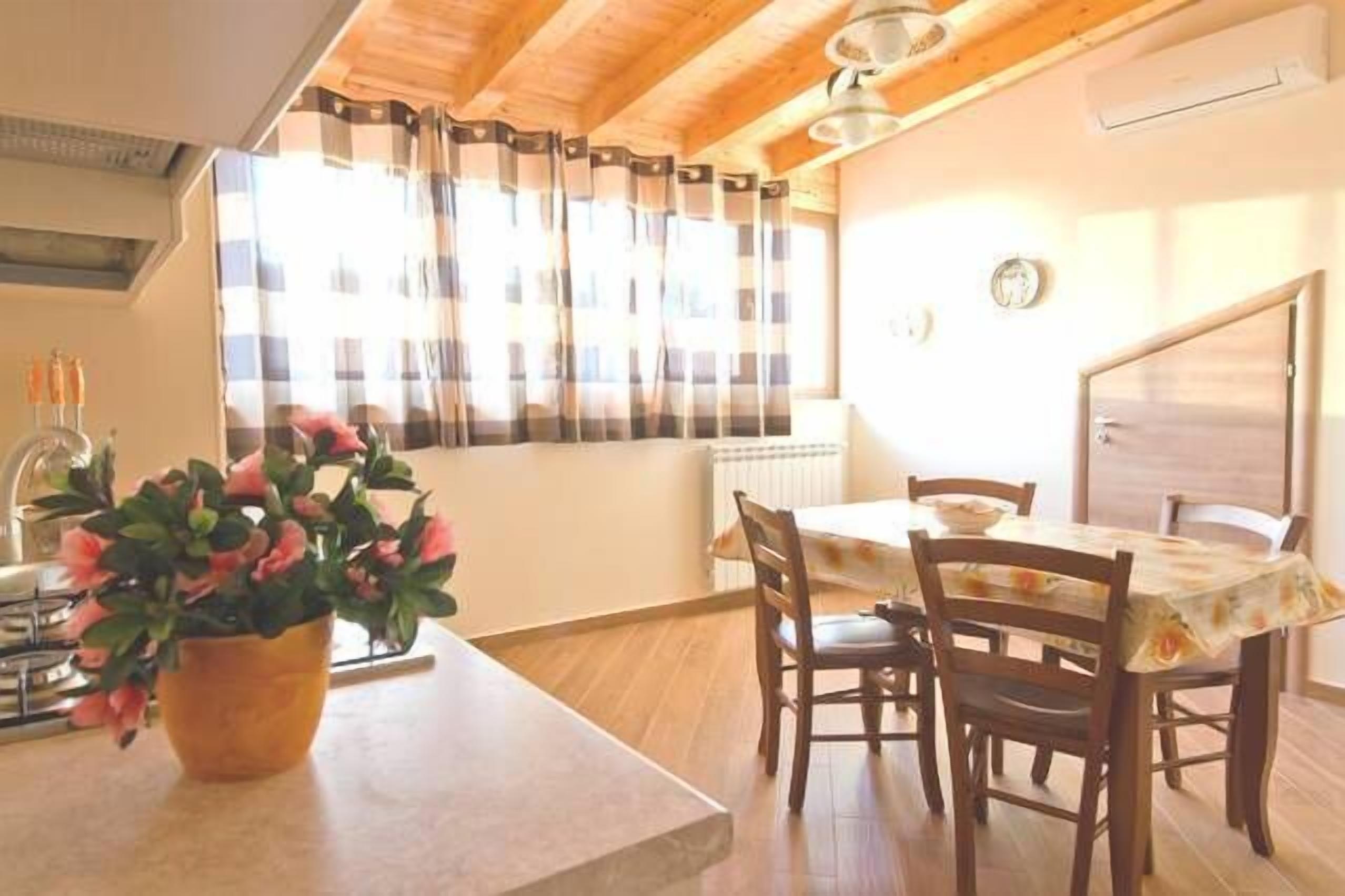 A dining area with a table and chairs, a potted plant, and a window with curtains.