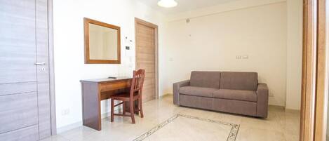 Um quarto com uma escrivaninha de madeira, um sofá marrom, um espelho e uma porta.