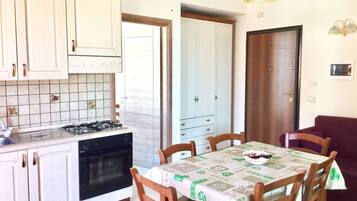 Una cocina con alacenas blancas, una estufa a gas y una mesa de comedor con sillas.