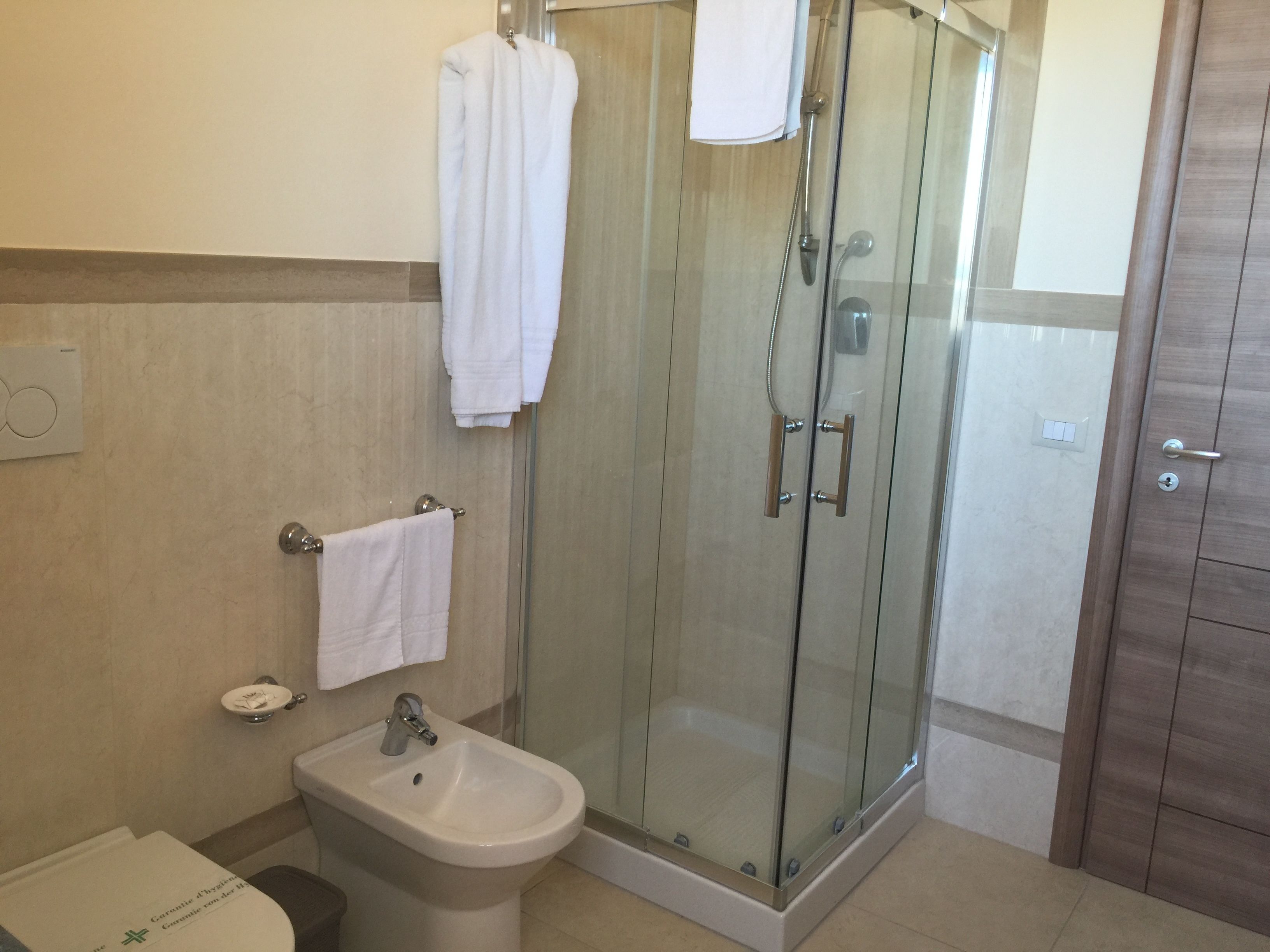 Un bany modern amb dutxa envidriada, un lavabo de pedestal i un escurapulides.