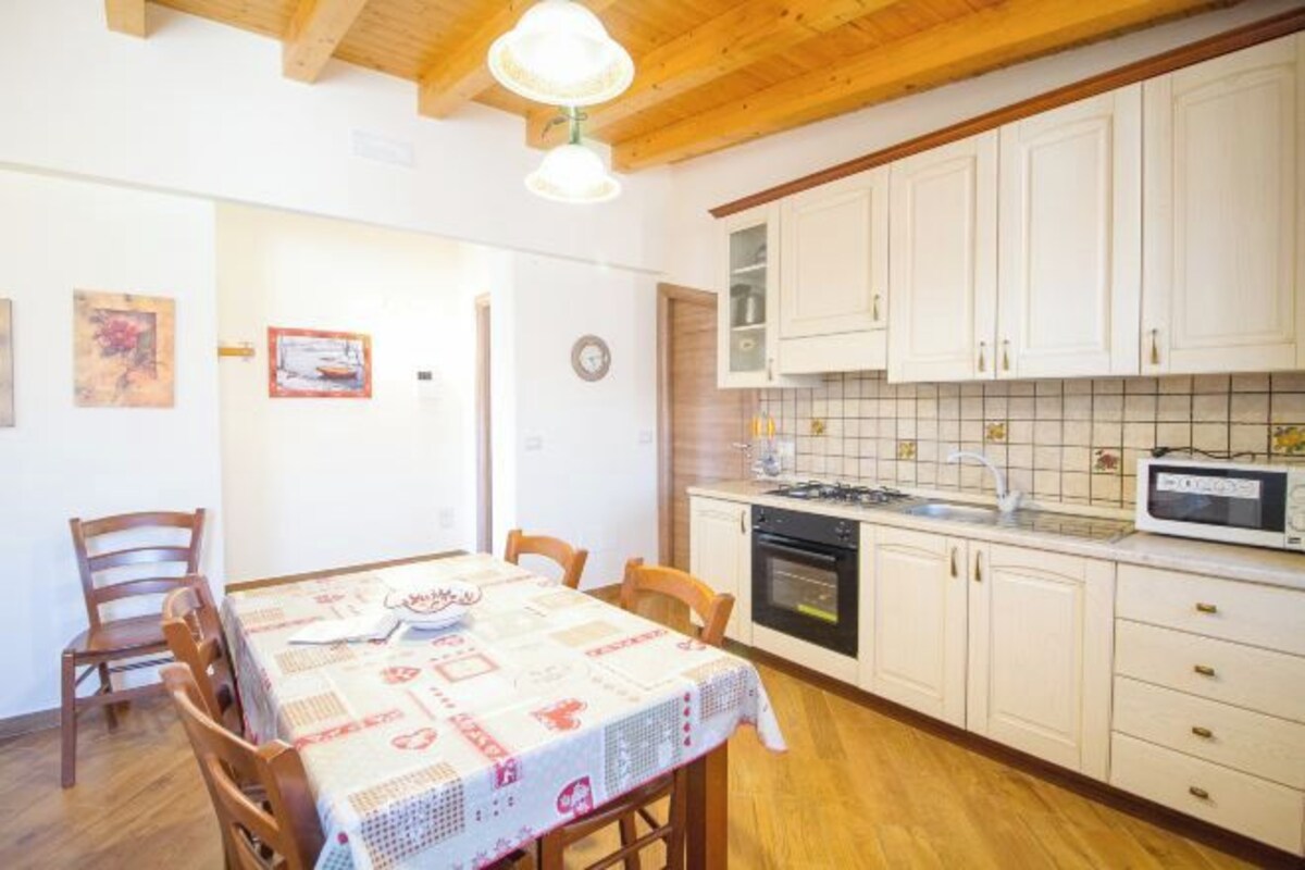 A kitchen with white cabinets, a microwave, and a dining table with chairs.