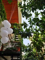 Un balcón con faroles blancos de papel, abundante follaje verde y baranda de madera.