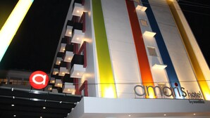 Ein Hotel mit moderner Fassade, die vertikale Streifen in verschiedenen Farben aufweist und beleuchtete Schilder trägt.