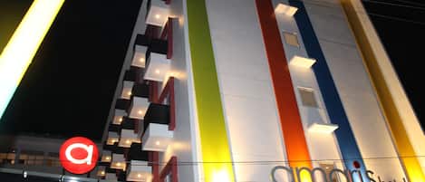 A hotel with a modern facade featuring vertical stripes in multiple colors and illuminated signage.
