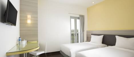 A hotel room with two beds, a glass table with a chair, a TV mounted on the wall, and a view of the outdoors through a door.