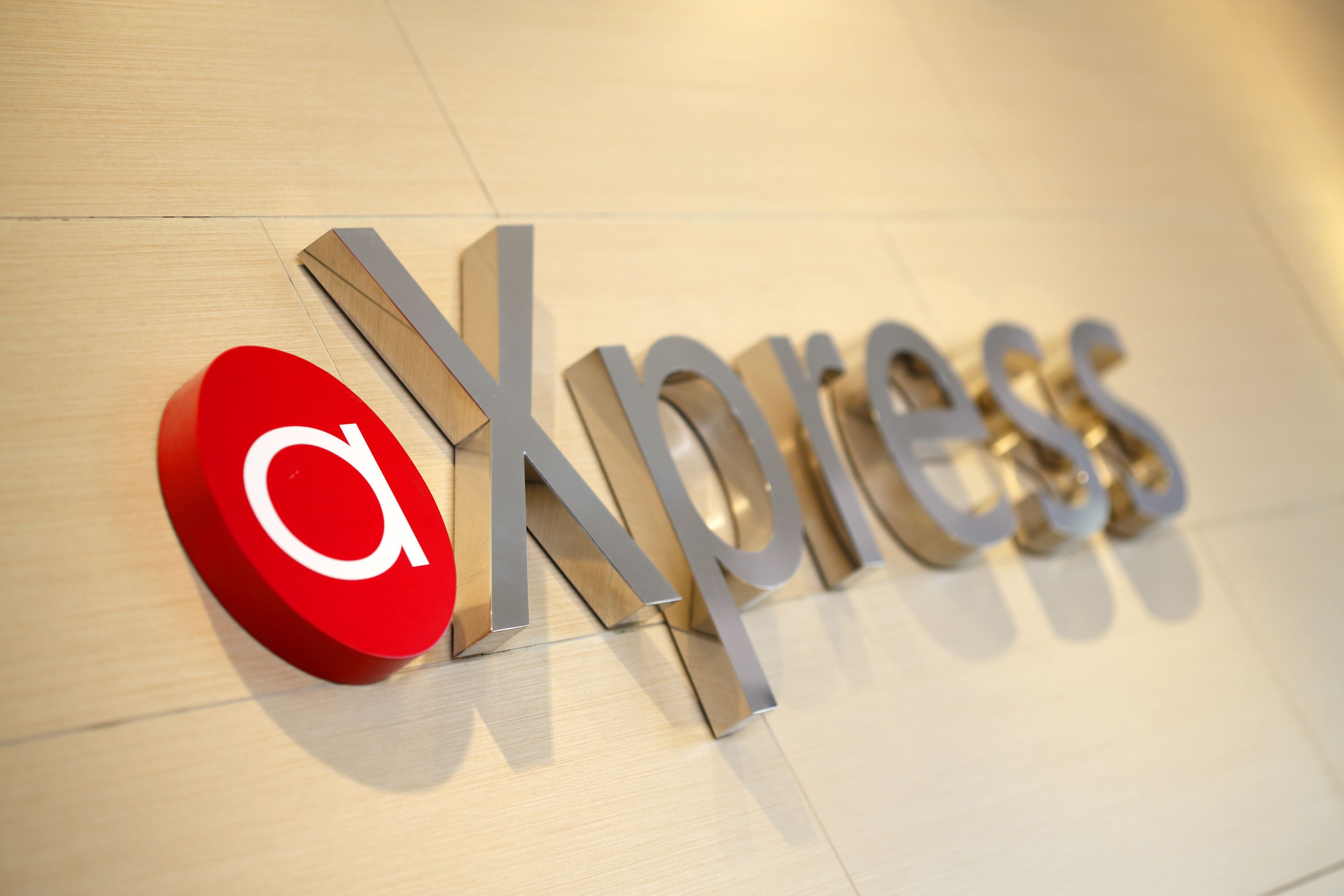 Un logotipo con las letras 'X' y 'press' sobre un piso de madera.