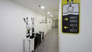 Een hotelgang met routeborden en een decoratieve knuffelkonijn.