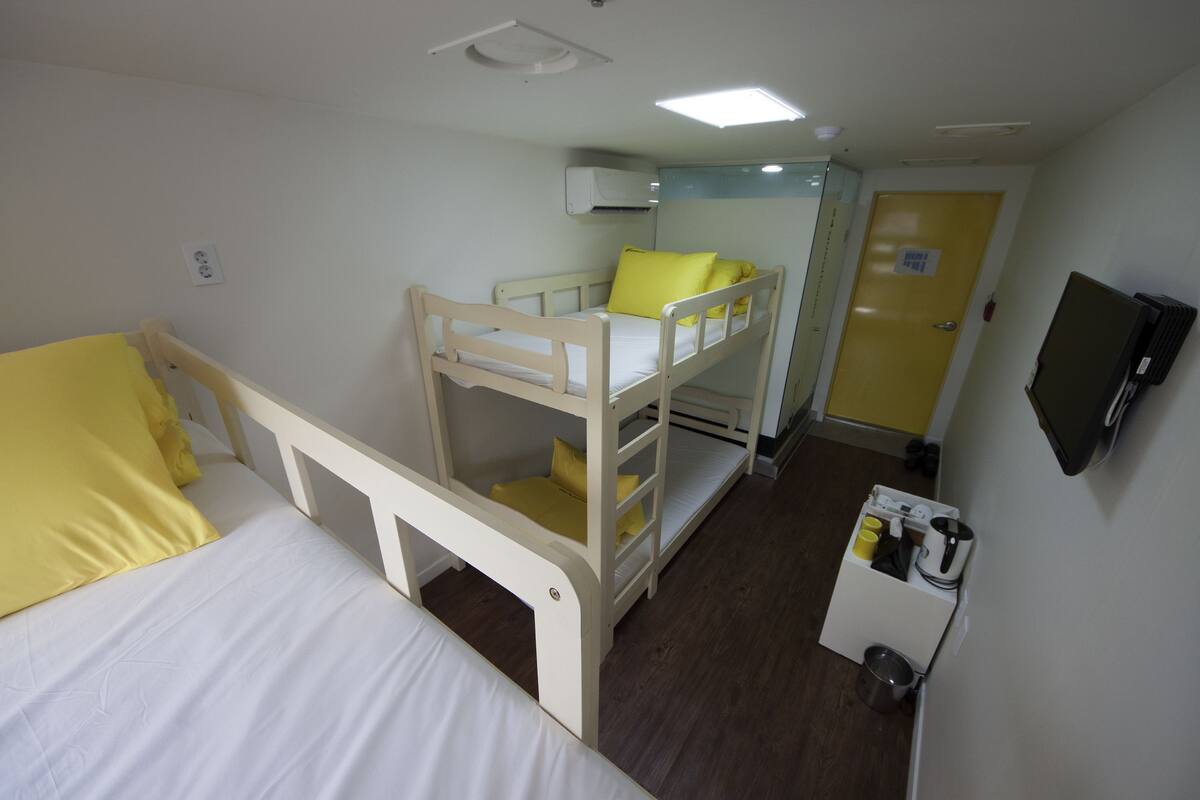 A bunk bed room with a desk and a television.