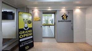Een hotel ingang met een bord voor de feestelijke opening, een receptiebalie en een etablissement open 24 uur per dag.
